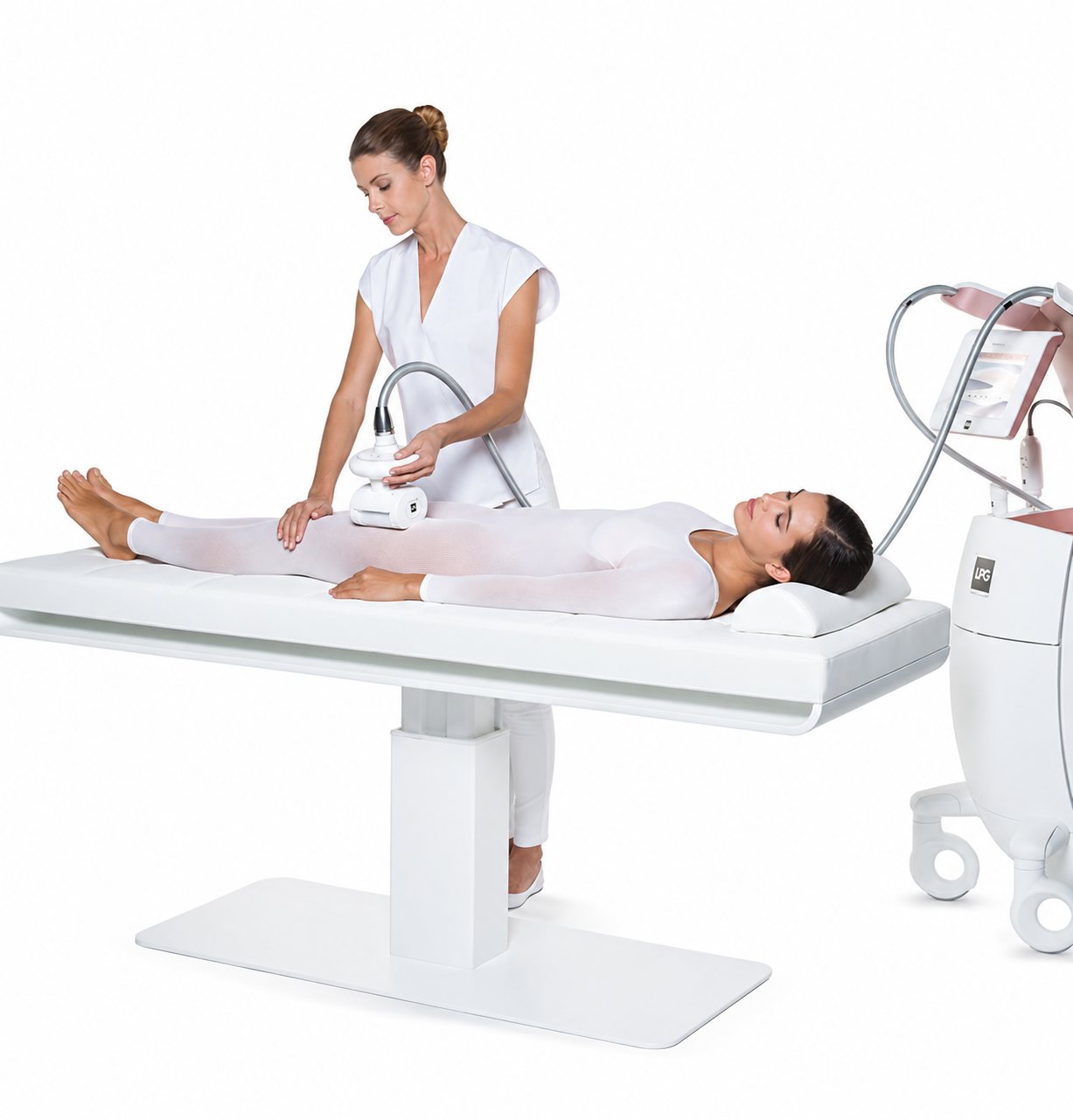 Une esthéticienne en blouse blanche pratique un soin avec un appareil de massage mécanique sur une femme allongée en combinaison blanche sur une table de soin.